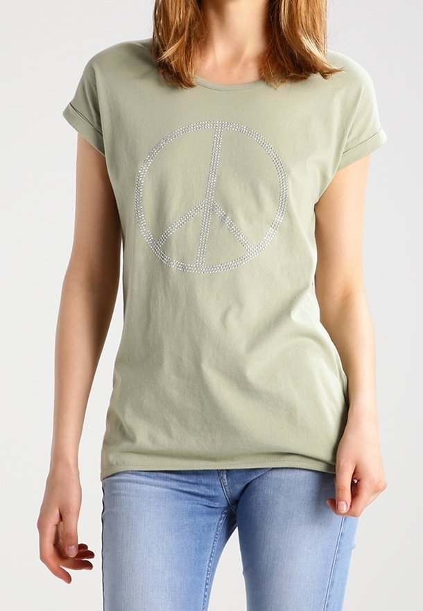 Světlá zelená bavlněná trička s ohrnutými rukávy. Uprostřed je velký symbol míru z kamínků. Kombinováno se světlými modrými džíny.