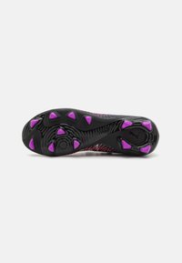 Soccer cleat outsole with a textured black surface, featuring purple studs arranged in a triangular pattern for traction.