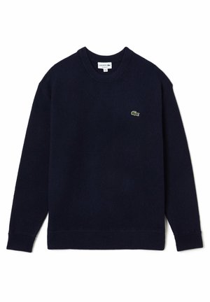 Granatowy sweter z okrągłym dekoltem i długimi rękawami, z małym zielonym logo krokodyla na lewej piersi.