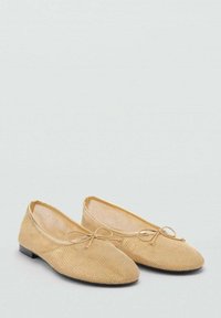 Musta ballerinat kevyessä kullassa, joissa on pyöreä varvas, hillitty rusetti edessä ja matala musta korko.