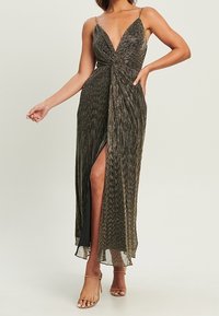 Mörk, texturerad maxiklänning med djup V-ringning, vriden framtill och hög slits som går till låret. Har tunna axelband och en flödande design.