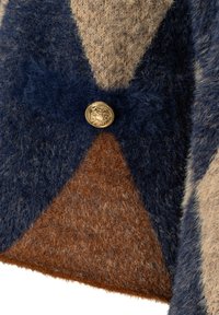 Close-up of a fuzzy knit garment with a geometric pattern in navy, beige, and brown, featuring a round gold button with decorative detail.