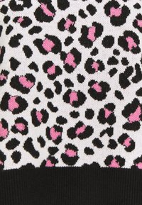 Pull en maille présentant un fond blanc avec un imprimé léopard noir et rose. L'ourlet est noir, avec une texture douce et une épaisseur moyenne.