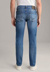 Jeans da uomo in denim blu con design a gamba dritta, dettagli nelle tasche posteriori e etichetta in pelle sul cinturino. Finiti con una superficie liscia.