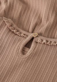 Tissu côtelé marron clair avec petit bouton en bois et encolure en trou de serrure, ornée d'une délicate bordure au crochet le long du bord.