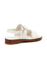 Sandal in pelle bianca con cinturino alla caviglia regolabile, fibbia argentata e suola in legno marrone. Design open-toe con ampie cinghie per supporto.