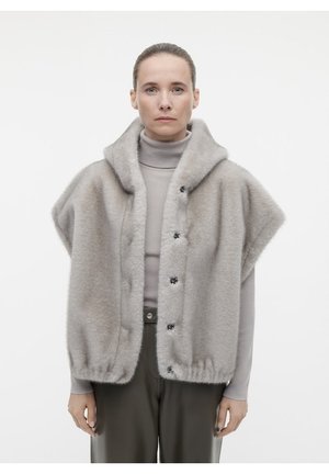 Gilet grigio chiaro in misto lana con colletto a scialle, maniche corte, chiusura a bottoni e una texture morbida, abbinato a un dolcevita sotto.