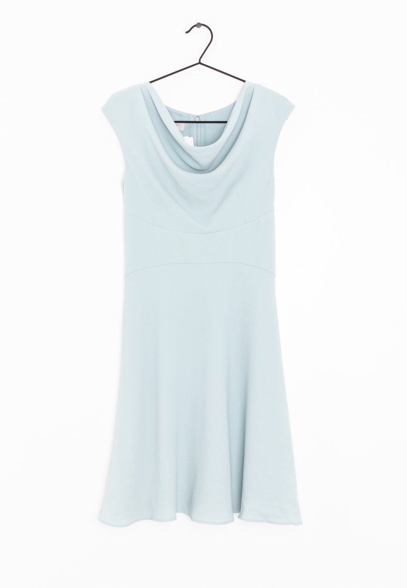 Robe bleu clair sans manches avec un col drapé, suspendue à un cintre noir sur un fond blanc.