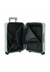 Valigia rigida di colore verde chiaro, con un interno a motivo nero, cinghie incrociate per il contenuto e tasca con zip. Manico estraibile e ruote.