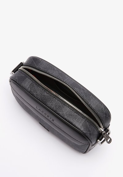 Pochette zippée noire en matériau durable, dotée d'une fermeture éclair argentée et d'un détail de logo embossé sur un côté.