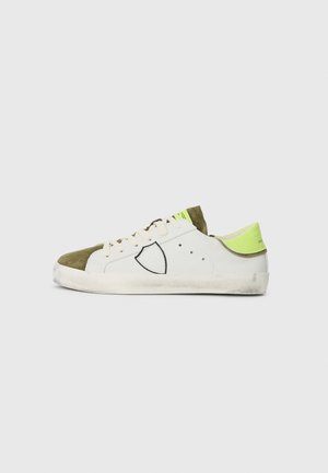Basket blanc et vert olive en matériaux daim et cuir, avec des coutures contrastées, des détails perforés et une accentuation vert néon sur le talon.