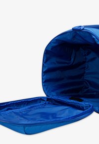 Blue nylon backpack with a spacious interior; smooth texture, top zipper closure, and a separate compartment with a soft lining.