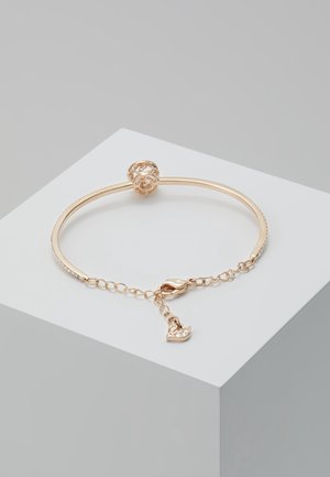 Delicate gold bracelet with a round openwork clasp, an adjustable chain, and a small swan-shaped charm with embedded crystals.