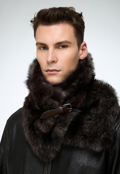 Pruun karusnahast krae pehme tekstuuriga, millel on pruun nahkrihm ja hõbedane pandlaga, kantud musta nahktagi peal.