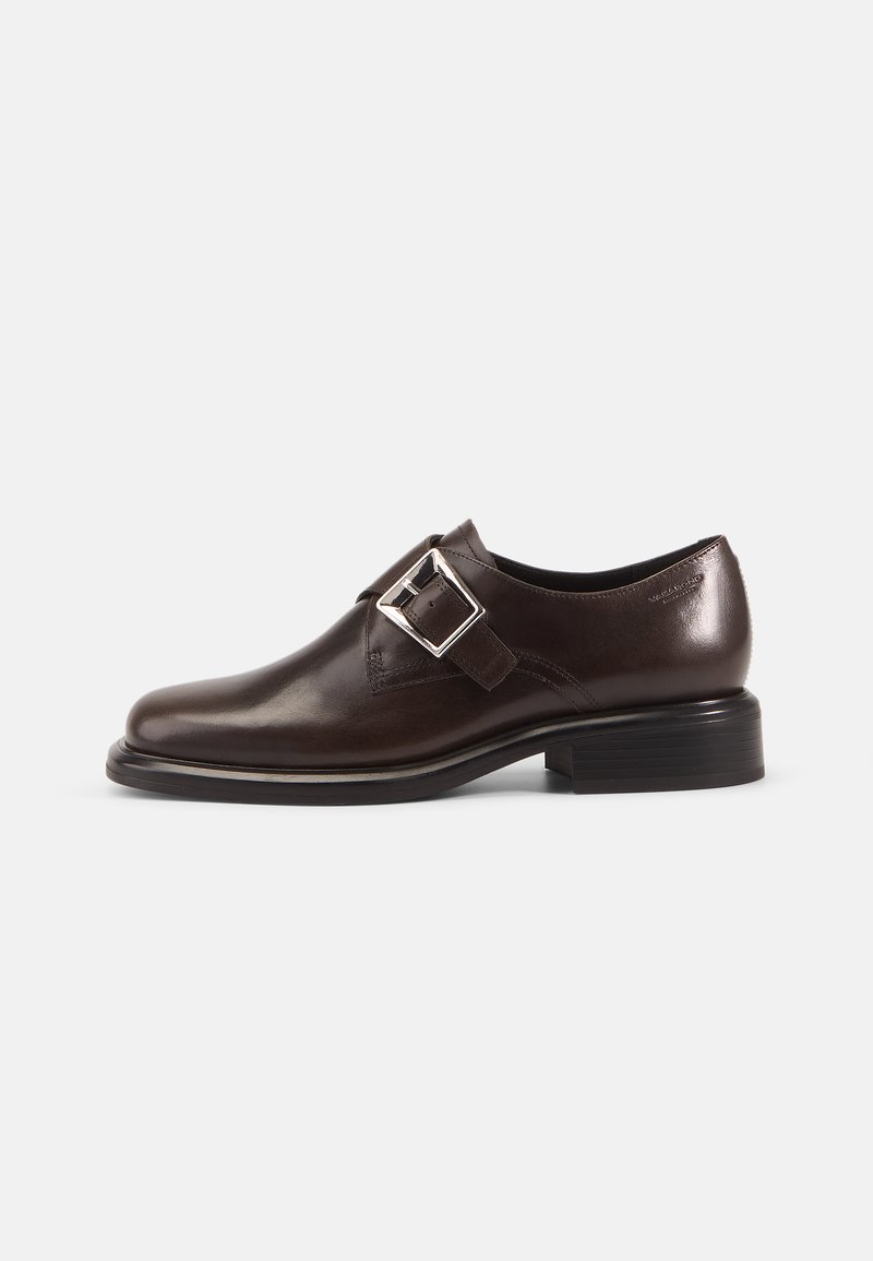 Brown leather shoe with a rounded toe, adjustable buckle detail, and a low stacked heel. Smooth finish and minimal design accents.