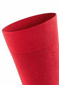 Rote gestrickte Socke mit strukturiertem Rippenmuster, breitem Bund oben für sicheren Halt und einem glatten Schaft für hohen Tragekomfort.