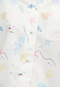 Λευκό πουκάμισο με παστέλ θαλασσινά σχέδια που περιλαμβάνουν μέδουσες, αστερίες, κοχύλια και μικρά πολύχρωμα ψάρια, με κουμπιά καλυμμένα με ύφασμα.