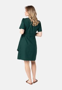 Zelené bavlněné šaty s krátkým rukávem, staženým pasem a délkou ke kolenům. Hladký texture, ležérní design a minimalistický styl.