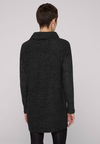 Morbido maglione grigio scuro a maniche lunghe con un ampio colletto e una vestibilità rilassata. Realizzato in un maglione lavorato a maglia soffice e testurizzato, arriva a metà coscia, con una leggera curvatura all'orlo.