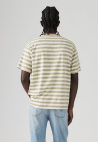 Camiseta de manga corta y cuello redondo con rayas horizontales en beige y verde. Fabricada con un tejido suave y con un corte relajado. Vista trasera mostrada.
