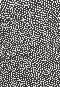 Tissu noir avec un motif géométrique blanc de petits carrés. Le matériau a une finition texturée avec des détails froncés.