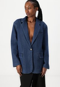 Temno moder denim suknjič s zapenjanjem na en gumb, zareznimi reverji, sprednjimi žepi in sproščenim krojem. Gladka tekstura in dolgi rokavi.