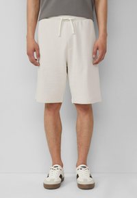 Shorts crème clair en tissu doux, avec une taille élastique à cordon de serrage, des poches latérales et une coupe droite.