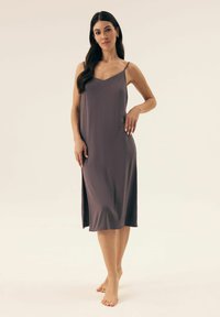 Sukienka midi bez rękawów w miękkim, stonowanym odcieniu mauve. Posiada dekolt w kształcie litery V, rozcięcie po boku oraz gładką strukturę z luźnym krojem.