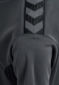 Grau atmungsaktiver Stoff mit strukturiertem schwarzen Einsatz und reflektierendem Chevron-Muster. Weiche, glatte Textur mit figurbetonten Designdetails.