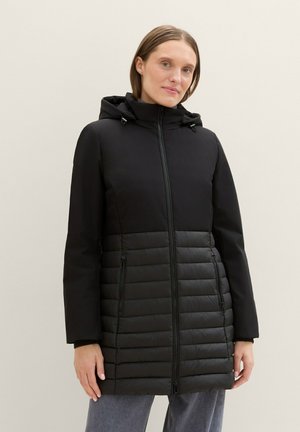 Schwarze Daunenjacke mit Kapuze, ausgestattet mit einem hohen Oberteil und einem gesteppten unteren Abschnitt, mit Reißverschlusstaschen und einem geraden Schnitt.