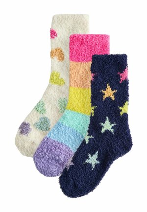 Three fuzzy socks with colorful patterns: one cream with multicolored hearts, one rainbow-striped, and one navy with multicolored stars.