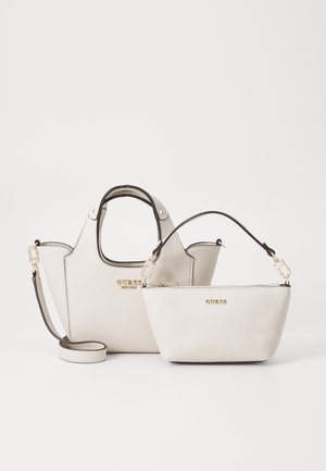 Twee witte, getextureerde Guess leren handtassen met gouden logo’s, één met korte handvatten en één met een lange afneembare riem, tegen een effen achtergrond.