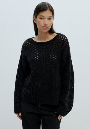 Schwarzer gestrickter Pullover mit lockerer Passform, der ein großes offenes Strickmuster und gerippte Bündchen aufweist. Der Ausschnitt ist weit und abgerundet.