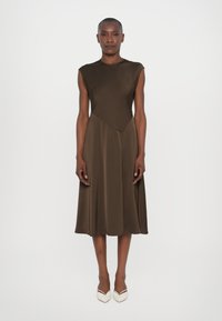 Rochie maro fără mâneci cu un design unghiular �și fustă evazată. Material neted și croială până la genunchi. Purtați-o cu tocuri bej cu vârf ascuțit.