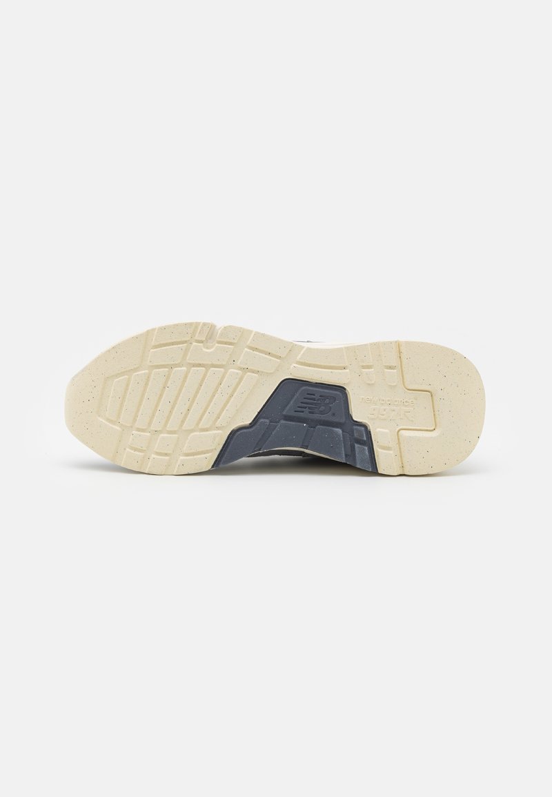 Graue und beige Sneaker-Sohle mit strukturiertem Gummigriff, detaillierten Profilmustern und "New Balance 992"-Branding an der Seite.