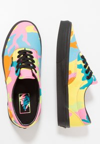Baskets Vans basses avec semelles et lacets noirs, présentant un motif camo abstrait multicolore en rose, bleu, jaune, orange et vert.