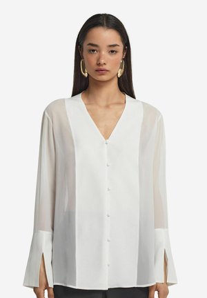 Weiße Bluse mit langen Ärmeln, tiefem V-Ausschnitt, Frontknöpfen und geschlitzten Manschetten; durchsichtiger Stoff mit glatter Textur; minimales Design.