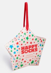 Scatola regalo a forma di stella con superficie bianca lucida, caratterizzata da motivi a stella rossi, verdi e blu, e una maniglia in nastro rosso. Include il marchio "HAPPY SOCKS".