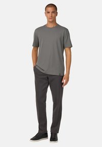 Grijze t-shirt met korte mouwen en een ronde hals, gecombineerd met donkergrijze broeken en zwarte sneakers. Minimalistisch ontwerp zonder zichtbare patronen.