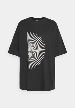 T-shirt oversize noir avec un motif blanc en forme de demi-étoile solaire présentant un visage détaillé sur le côté gauche de la poitrine.