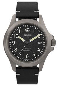 Reloj de titanio con esfera negra texturizada, números árabes blancos, manecillos plateados y correa de cuero negra; cuenta con visualización de la fecha y resistencia a los golpes.