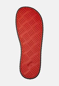 Red rubber shoe sole with a textured pattern of raised rectangles and squares. Black edge outlining the sole. Size 38 marked on the sole.