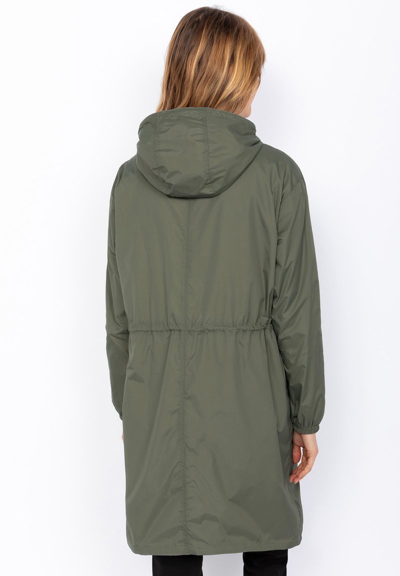 Veste verte à capuche avec une taille cintrée, fabriquée dans un matériau léger. Présente des manches longues et un design mi-long. Texture lisse.