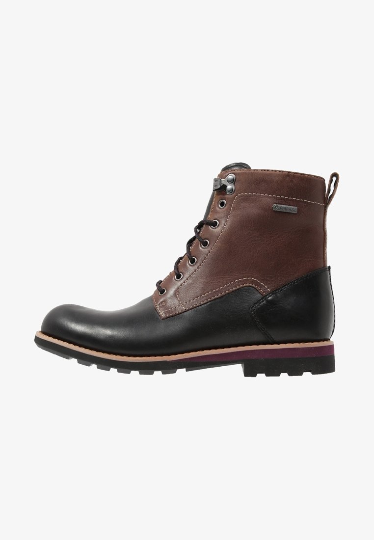 Bottine pour homme en cuir bicolore avec bout noir, partie supérieure marron, devant à lacets, semelle à crampons, et étiquette Gore-Tex étanche.