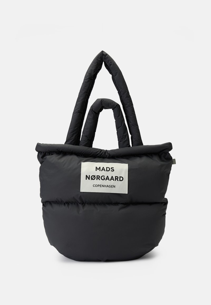 Sac cabas noir matelassé avec deux paires de poignées, portant une étiquette blanche avec le texte "Mads Nørgaard Copenhagen" à l'avant.