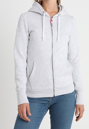 Sudadera con cremallera de color gris claro, hecha de una suave tela texturada, que cuenta con un bolsillo frontal, capucha ajustable con cordón y puños acanalados.