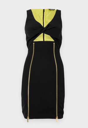 Čierne šaty s žltým panelom, predným zatočením a zlatými zipsami na bokoch pre zvýraznenie dizajnového kontrastu.