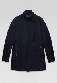 Abrigo azul marino con cuello alzado, textura suave y dos bolsillos laterales con cremallera. Diseño de corte recto con detalles de costuras sutiles.