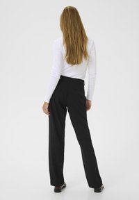 Pantaloni neri su misura con gamba dritta e tessuto morbido, dotati di una vita aderente e due tasche posteriori.