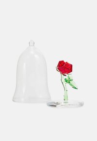 Glasstor som täcker en röd kristallros med gröna blad på ett genomskinligt stativ. Släta, blanka ytor och geometriska former.